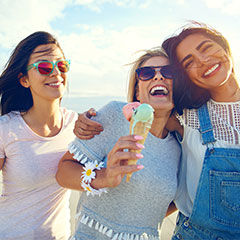 Three women having fun eating ice cream at the beach